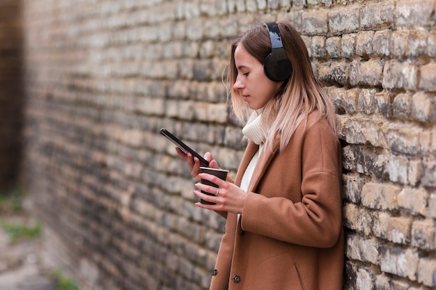 Kostenloses Foto junge blonde frau, die musik auf kopfhörern mit exemplarplatz hört