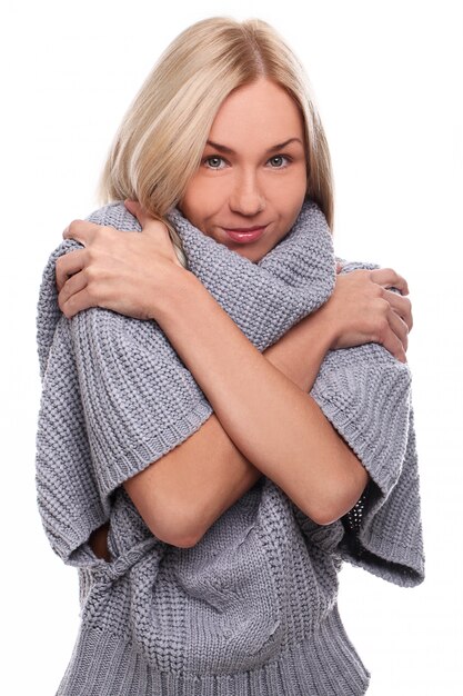 Junge blonde Frau, die sich mit einem Pullover bedeckt