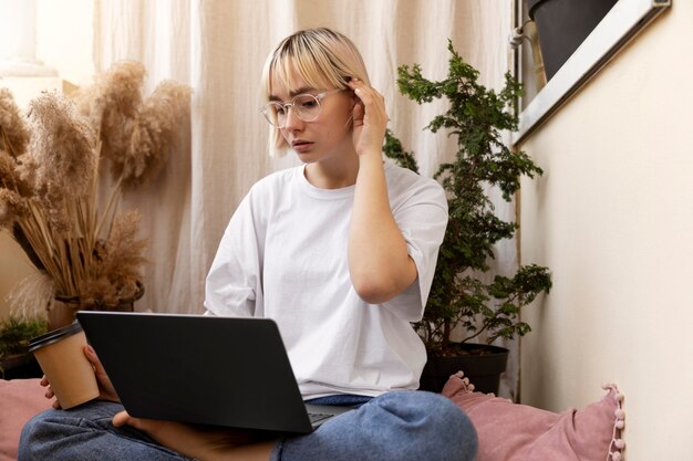 Junge blonde Frau, die von zu Hause aus auf dem Boden arbeitet