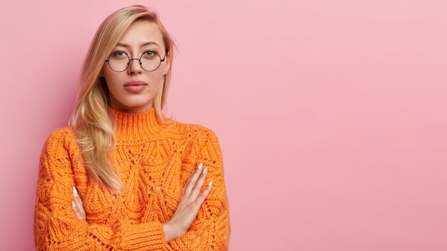 Junge blonde Frau im orangefarbenen Pullover