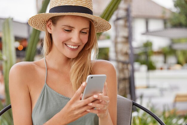 Junge blonde Frau im Strohhut, der in einem Café sitzt