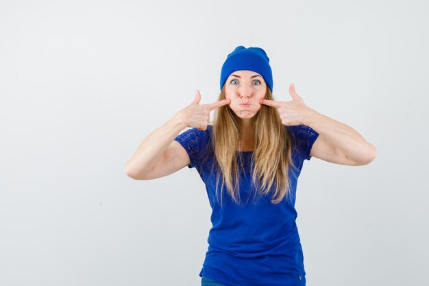 Junge blonde Frau in einem blauen T-Shirt und einem Hut