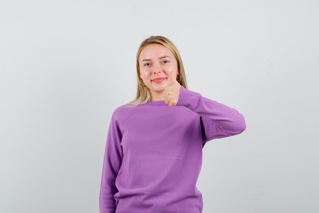 Junge blonde Frau in einem lila Pullover