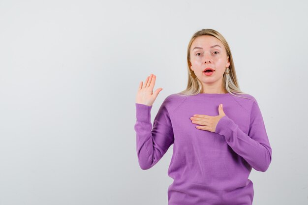 Junge blonde Frau in einem lila Pullover