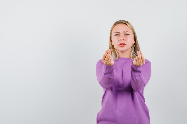 Junge blonde Frau in einem lila Pullover