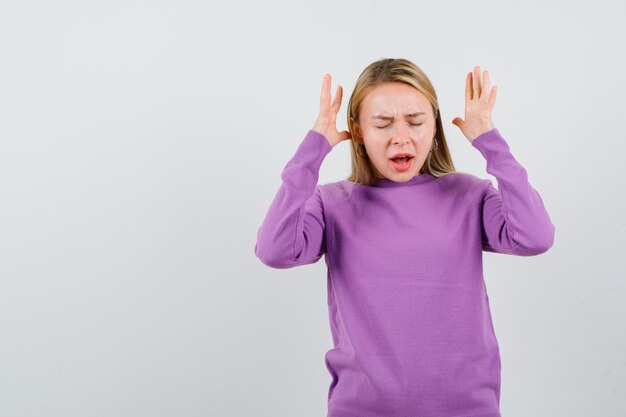 Junge blonde Frau in einem lila Pullover