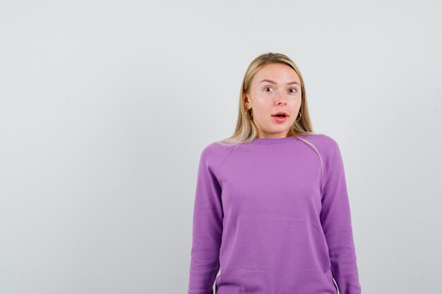 Junge blonde Frau in einem lila Pullover