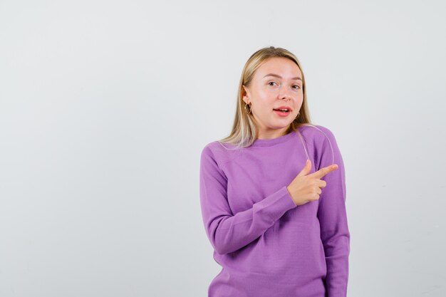 Junge blonde Frau in einem lila Pullover