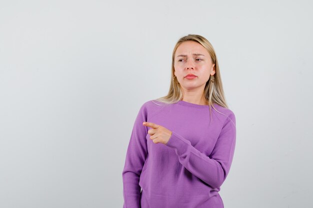 Junge blonde Frau in einem lila Pullover