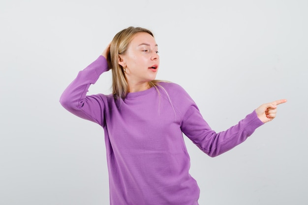 Junge blonde Frau in einem lila Pullover