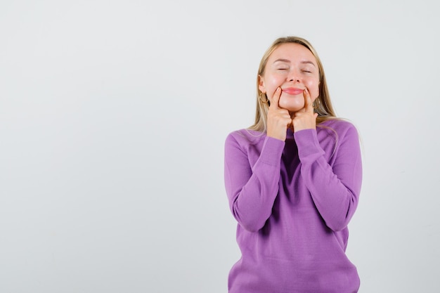 Junge blonde Frau in einem lila Pullover