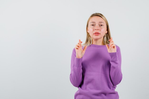 Junge blonde Frau in einem lila Pullover