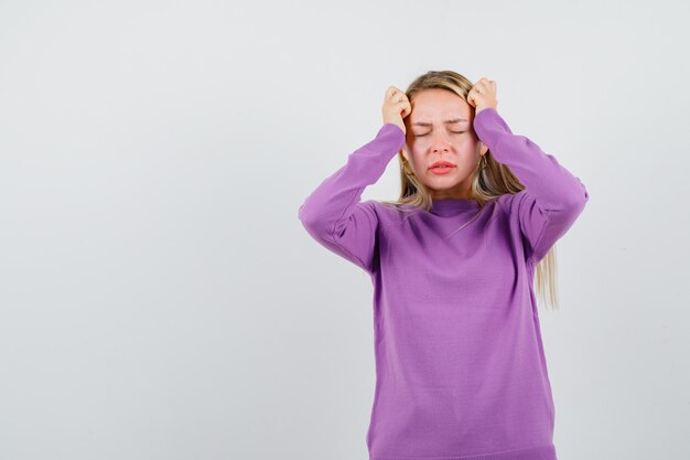 Junge blonde Frau in einem lila Pullover