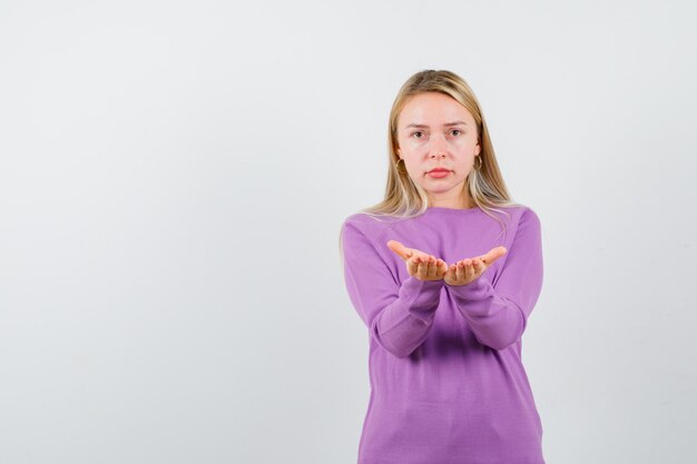 Junge blonde Frau in einem lila Pullover