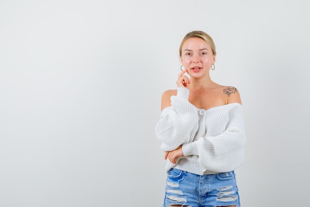 Junge blonde Frau in einem weißen Pullover