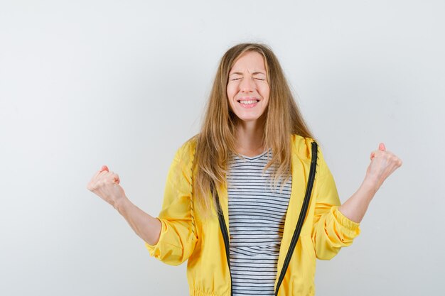 Junge blonde Frau in einer gelben Jacke