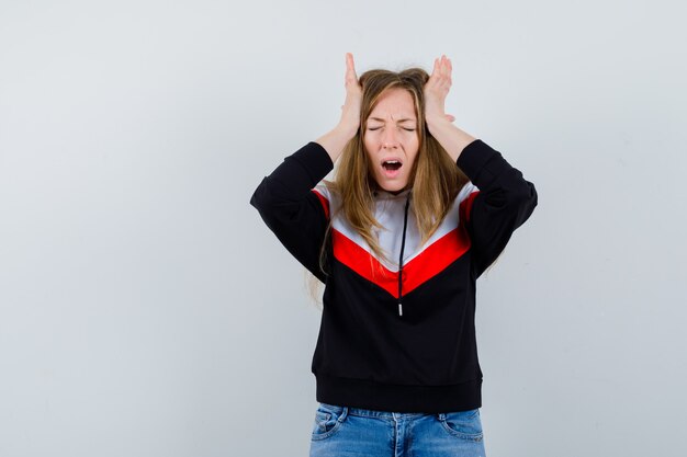 Junge blonde Frau in einer Jacke und in Jeans