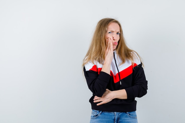 Junge blonde Frau in einer Jacke und in Jeans