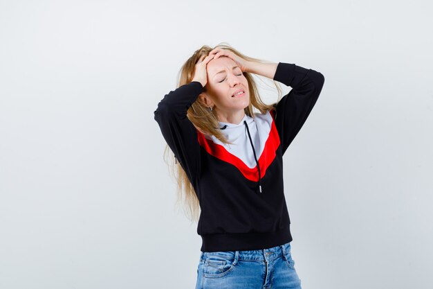 Junge blonde Frau in einer Jacke und in Jeans