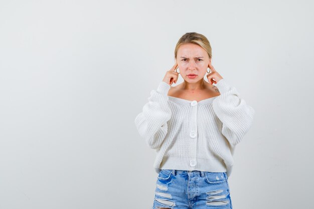 Junge blonde Frau in einer weißen Strickjacke