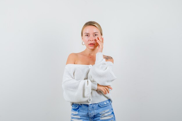 Junge blonde Frau in einer weißen Strickjacke