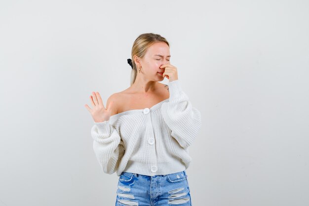 Junge blonde Frau in einer weißen Strickjacke