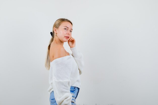 Junge blonde Frau in einer weißen Strickjacke