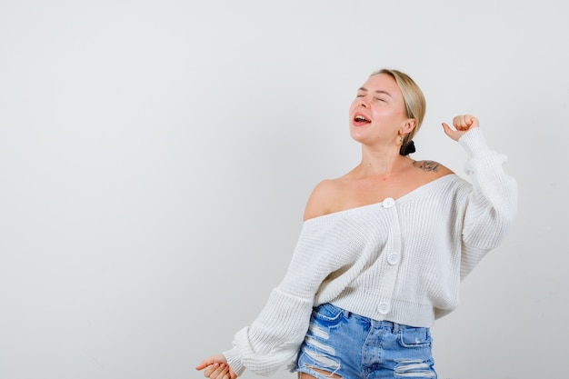 Junge blonde Frau in einer weißen Strickjacke