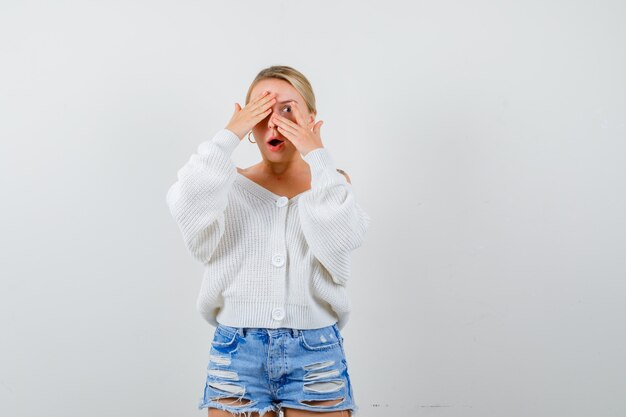 Junge blonde Frau in einer weißen Strickjacke