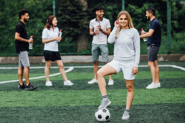 Junge, blonde Frau lächelnd und glücklich, mit Fußball, aufgeregt, ein Spiel zu spielen