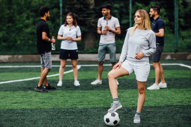 Junge, blonde Frau lächelnd und glücklich, mit Fußball, aufgeregt, ein Spiel zu spielen