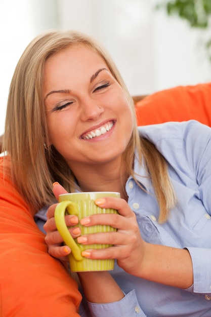 Junge blonde Frau mit Becher