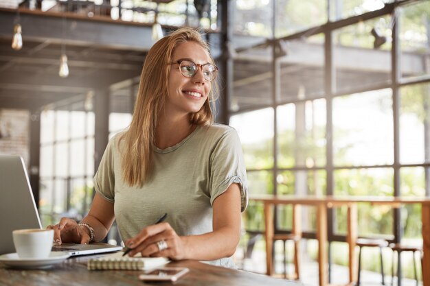 Junge blonde Frau mit Brille im Café