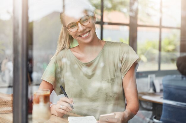 Junge blonde Frau mit Brille im Café