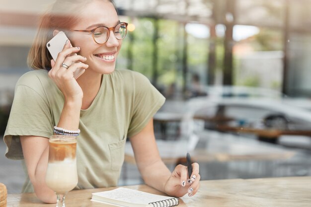 Junge blonde Frau mit Brille im Café