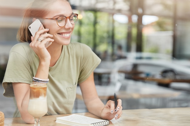 Junge blonde Frau mit Brille im Café