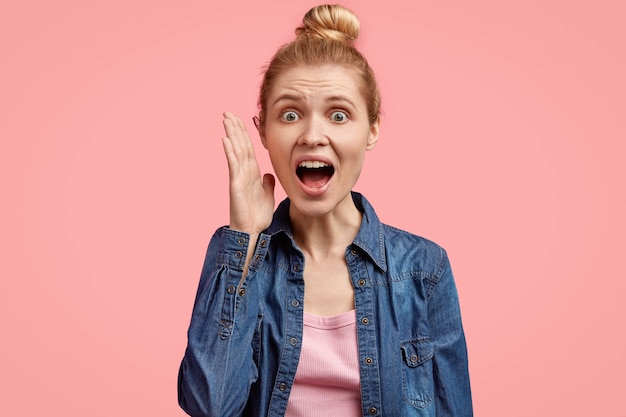 Junge blonde Frau mit den Haaren im Brötchen und im Jeanshemd