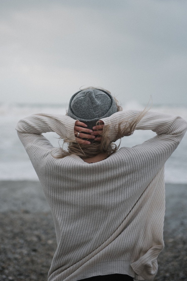 Kostenlose Foto junge blonde frau mit einem hut am strand bei windigem wetter