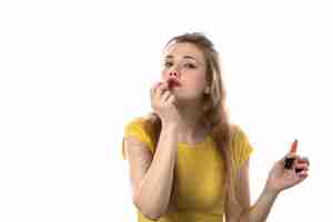 Kostenloses Foto junge blonde frau mit gelbem t-shirt unter verwendung des lippenstifts