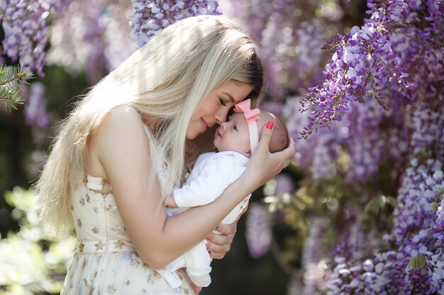 junge blonde Mutter mit neugeborenem Baby im Freien