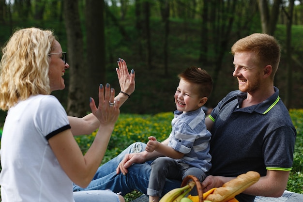 Junge blonde Mutter spielt mit ihrem Sohn während eines Picknicks im Park