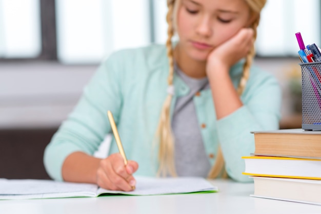 Junge blonde Studentin, die drinnen schreibt