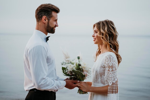 Junge Braut und Bräutigam, die eine Strandhochzeit haben