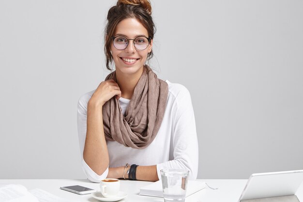 Junge brünette Frau, die am Schreibtisch sitzt