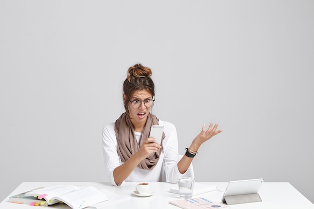 Junge brünette Frau, die am Schreibtisch sitzt