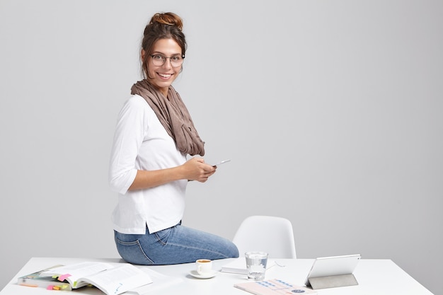 Junge brünette Frau, die am Schreibtisch sitzt