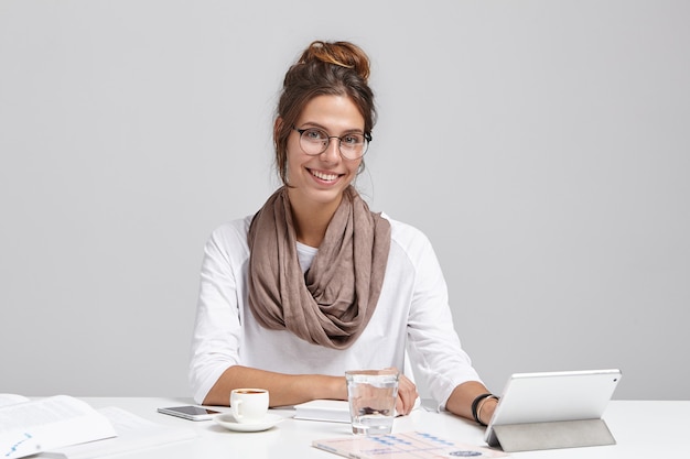 Junge brünette Frau, die am Schreibtisch sitzt