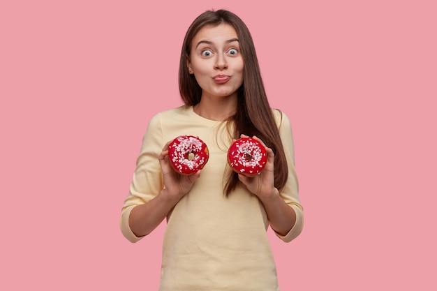 Junge brünette Frau, die leckere Donuts hält