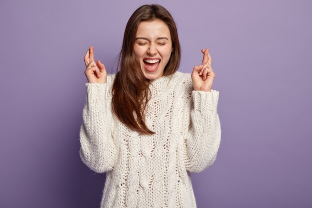 Junge brünette Frau, die weißen Pullover trägt