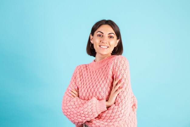 Junge Brünette im rosa Pullover lokalisiert auf blauer Wand